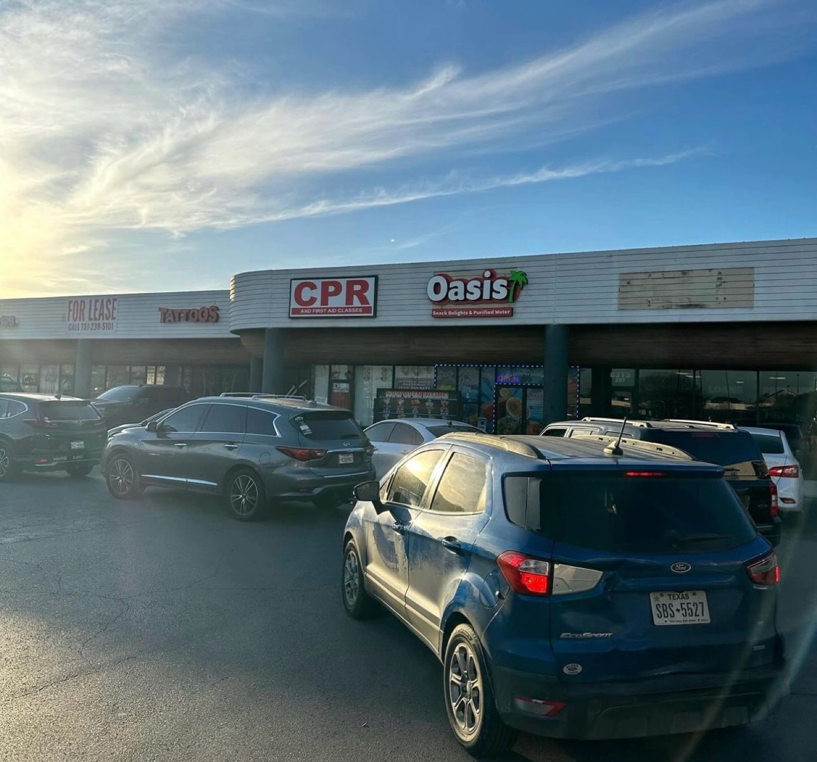 The Oasis Snack Delights storefront in the Culebra Road plaza at dusk